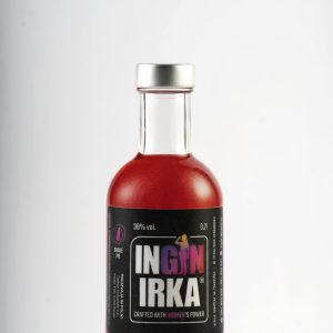 Bottle of red liquid with a black label featuring bold white-and-pink lettering and a silver cap, photographed against a light background.